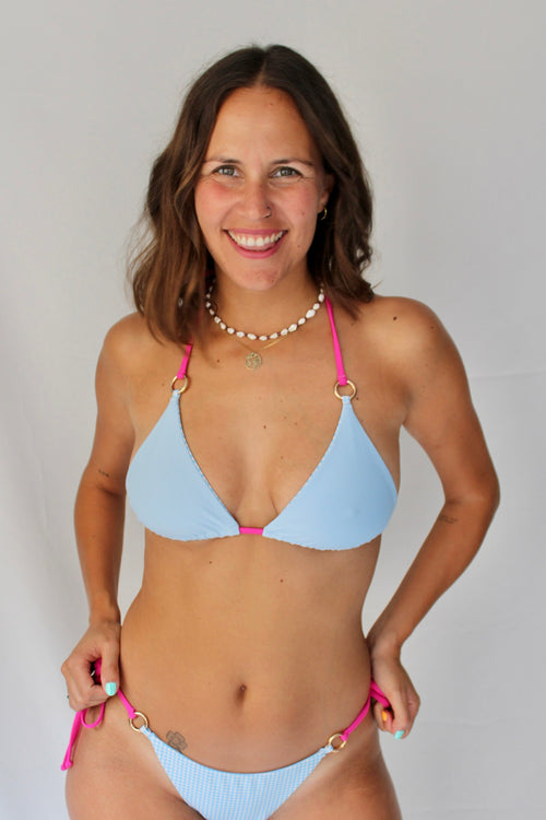 Modelo con bikini reversible azul liso con tiras intercambiables color fucsia