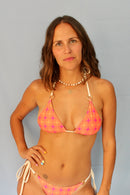 Modelo con bikini reversible estampado naranja y fucsia con tiras intercambiables beige