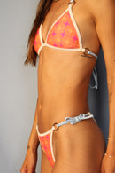 Modelo con bikini estampado naranja y fucsia con tiras intercambiables color azules